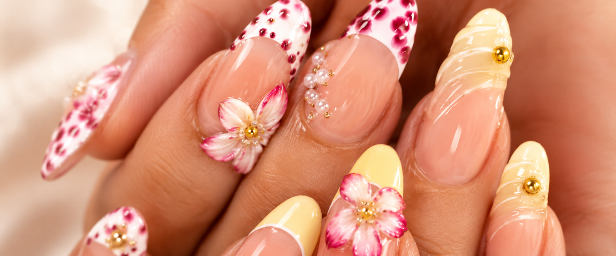 Glossy nude almond nails with pink floral French tips, yellow accents, 3D flowers and pearl details by Mariana Nails in Saipan