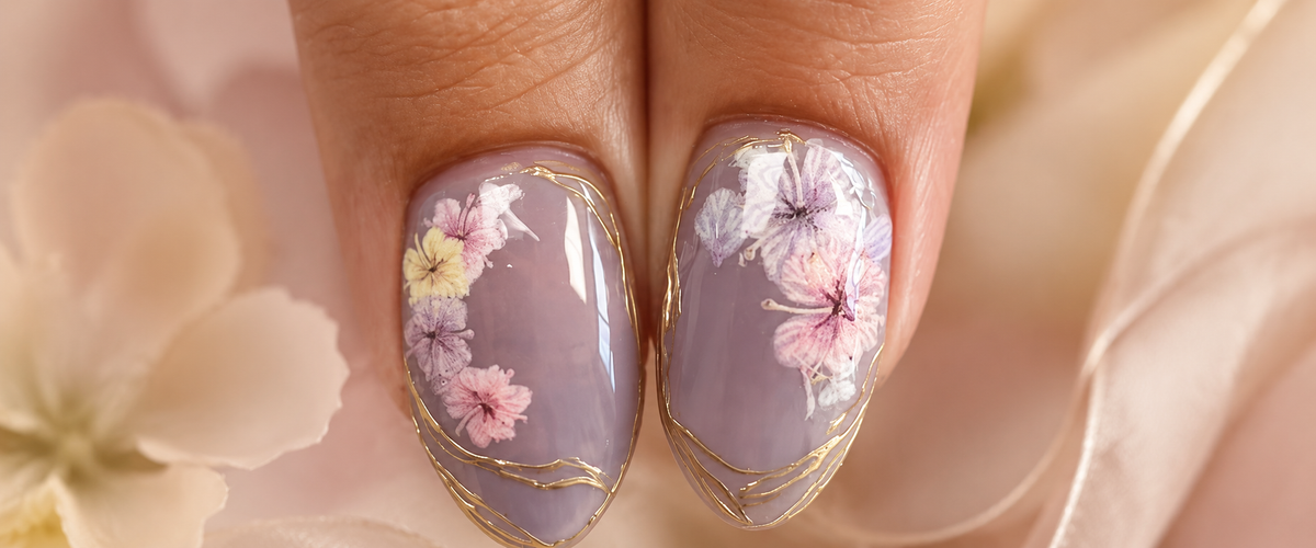 Lavender almond nails with pressed pink floral art and delicate gold foil accents by Mariana Nails in Saipan